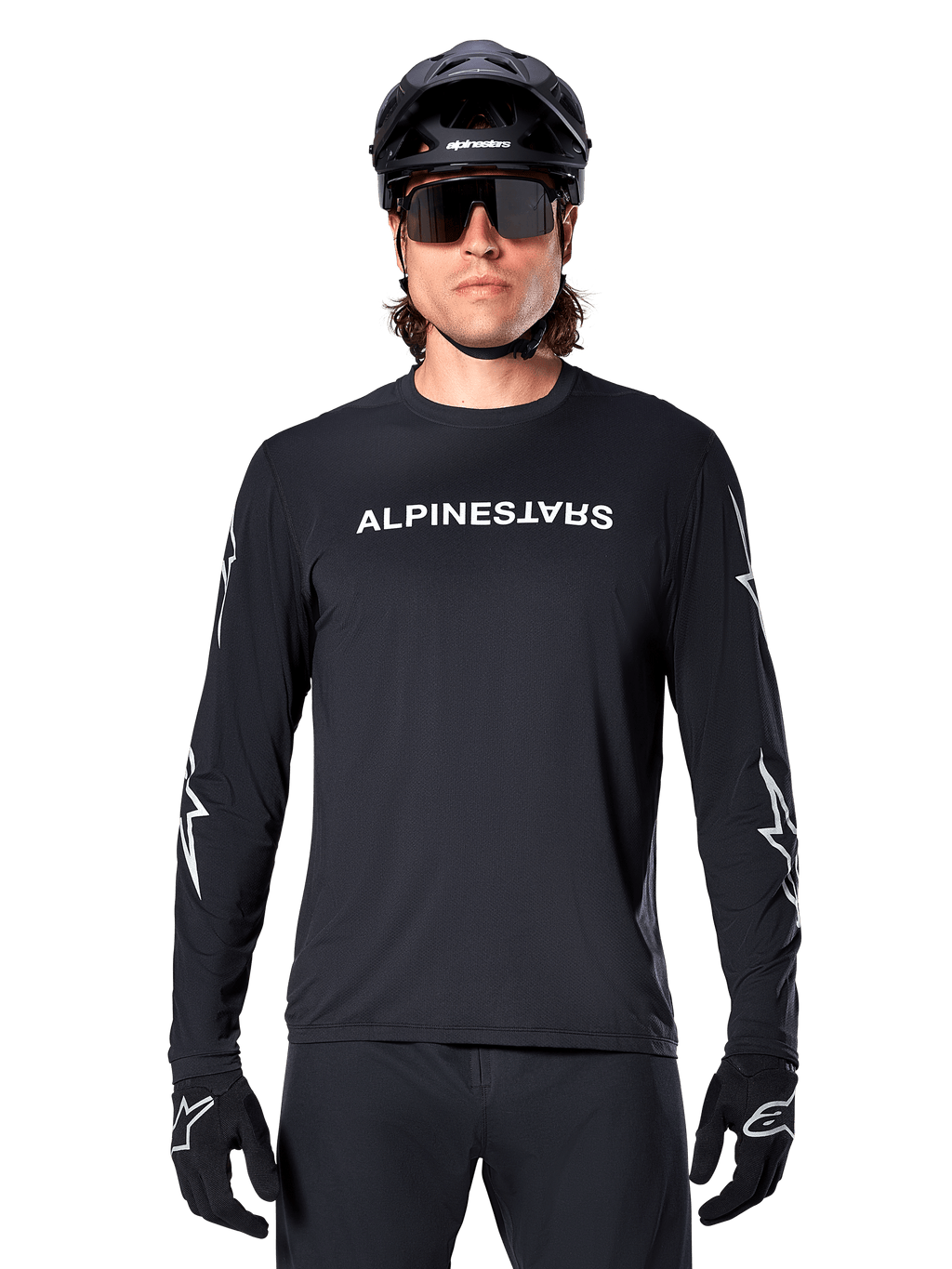 Alpinestars A-Dura Switch långärmad tröja, svart MTB-tröja, vit Alpinestars-ordmärkeslogotyp på bröstet och stjärngrafik på ärmarna, bärs med svart mountainbikehjälm och sportglasögon, tekniska kläder för stigcykling