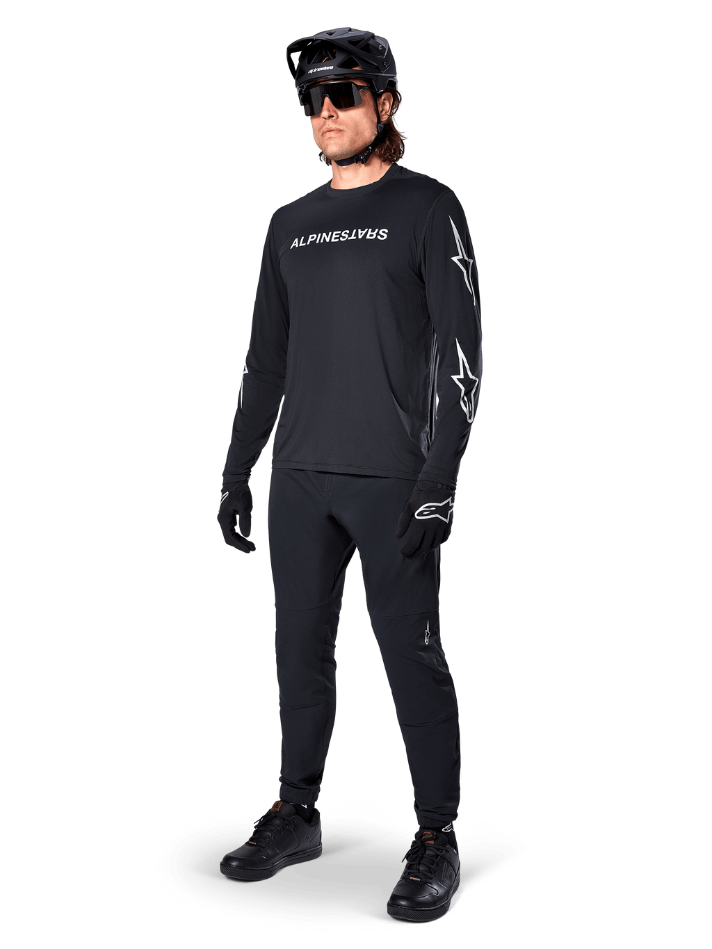 Alpinestars A-Dura Switch långärmad tröja, svart, mountainbiketröja bärs med svarta byxor, hjälm och handskar, vit ordmärkeslogotyp på bröstet och stjärnlogotyper på ärmarna, matchande MTB-utrustning för terrängkörning