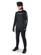 Alpinestars A-Dura Switch långärmad tröja, svart, mountainbiketröja bärs med svarta byxor, hjälm och handskar, vit ordmärkeslogotyp på bröstet och stjärnlogotyper på ärmarna, matchande MTB-utrustning för terrängkörning