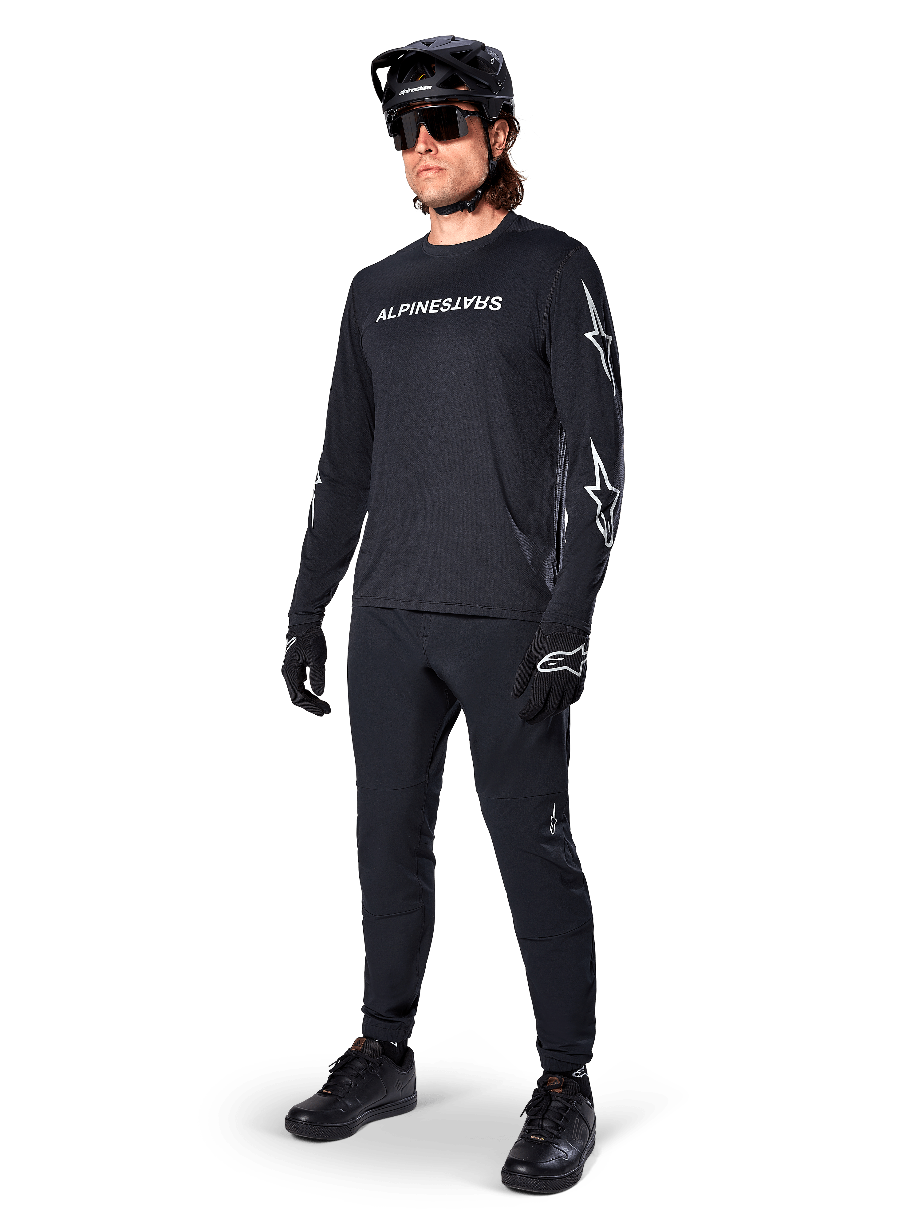 Alpinestars A-Dura Switch långärmad tröja, svart, mountainbiketröja bärs med svarta byxor, hjälm och handskar, vit ordmärkeslogotyp på bröstet och stjärnlogotyper på ärmarna, matchande MTB-utrustning för terrängkörning
