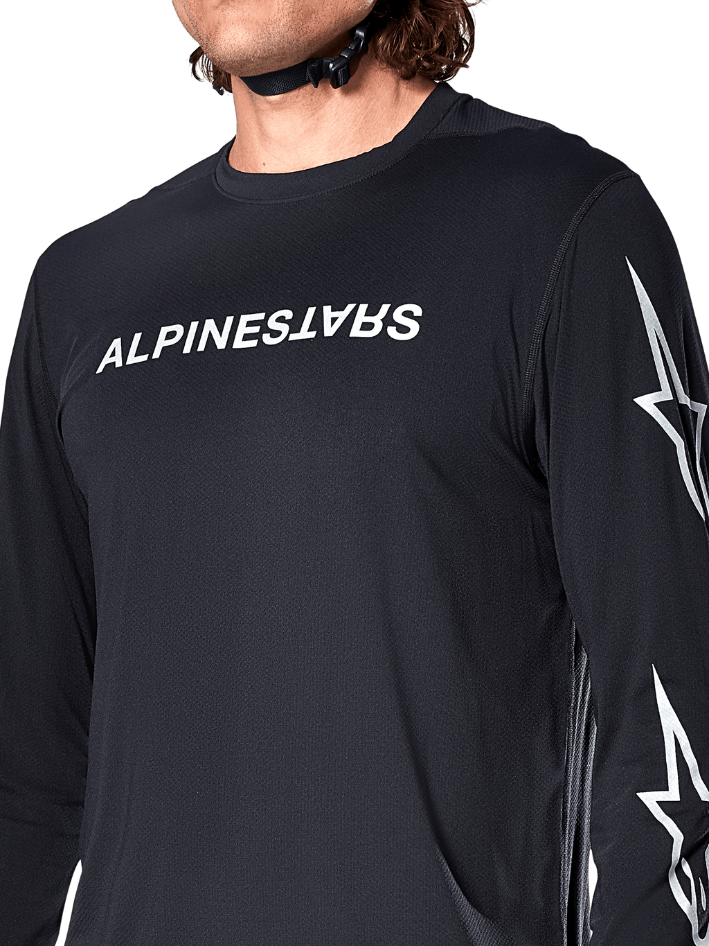 Alpinestars A-Dura Switch långärmad tröja, svart, med vit Alpinestars-ordmärkeslogotyp på bröstet och stjärnlogotyper på ärmen, buren av en cyklist med synlig hjälmrem, tekniska mountainbike-kläder