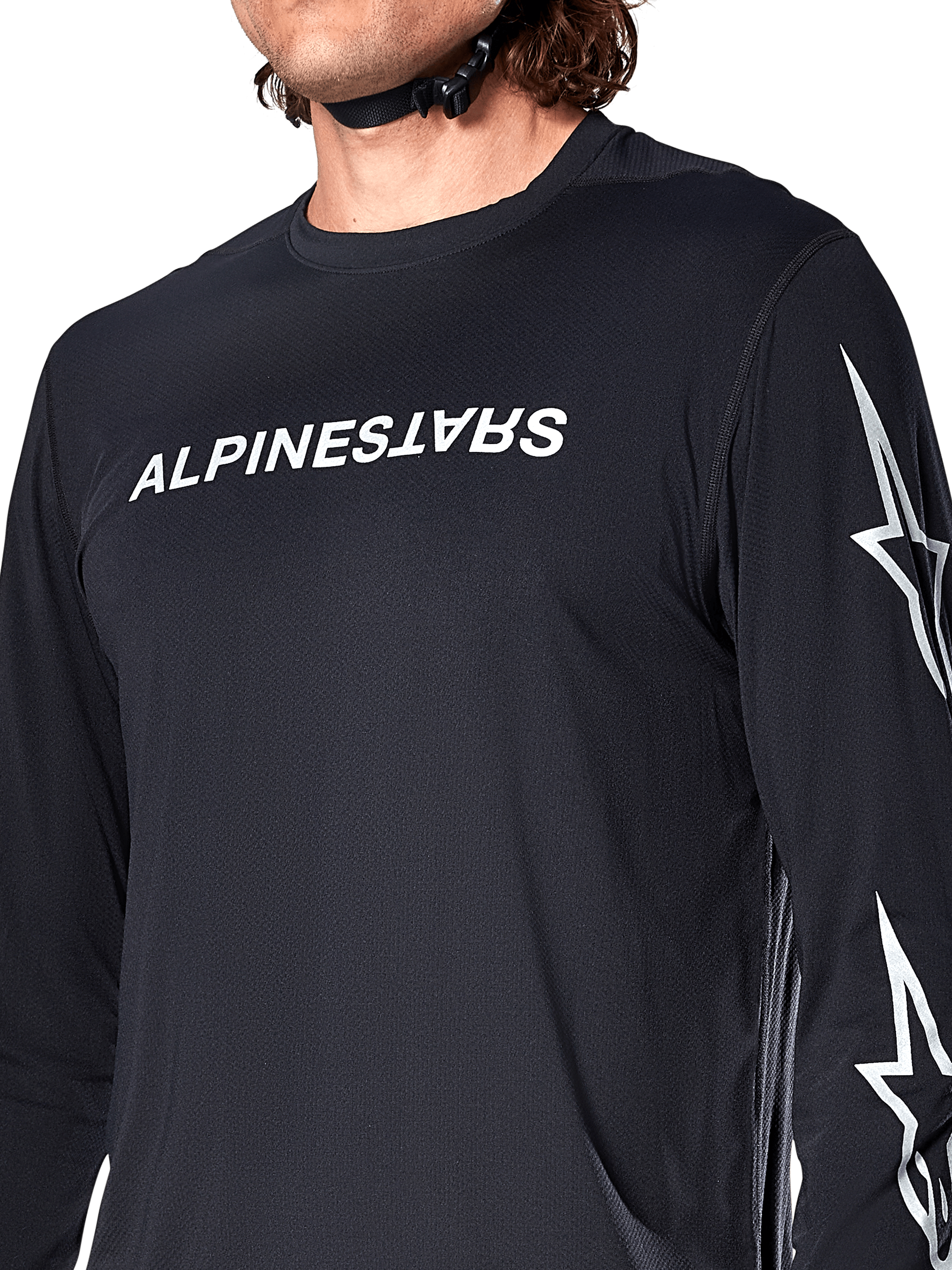 Alpinestars A-Dura Switch långärmad tröja, svart, med vit Alpinestars-ordmärkeslogotyp på bröstet och stjärnlogotyper på ärmen, buren av en cyklist med synlig hjälmrem, tekniska mountainbike-kläder