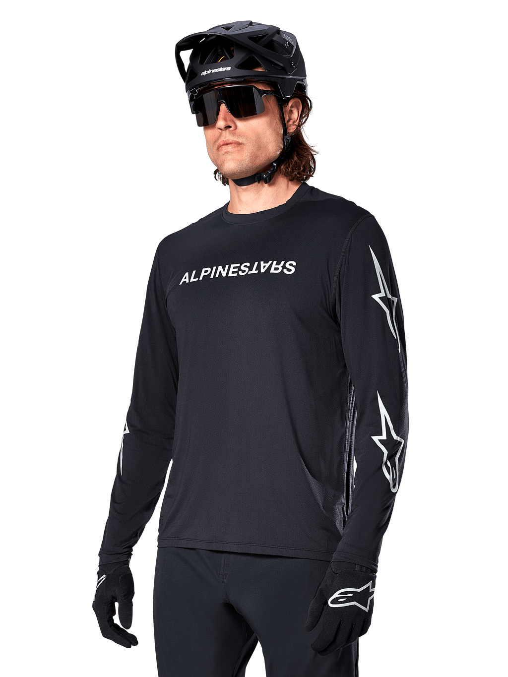 Manlig cyklist i Alpinestars A-Dura Switch långärmad tröja, svart med vit ordmärkeslogotyp och stjärnlogotyper på ärmarna, kombinerad med svart MTB-hjälm och solglasögon, högpresterande cykelutrustning för terrängcykling