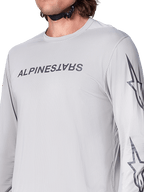Alpinestars A-Dura Switch långärmad tröja, ljusgrå mountainbiketröja med mörkgrått ordmärke på bröstet och stjärnlogotyp på ärmen, ventilerande jacquard-textur, teknisk cykelutrustning för stigcykling