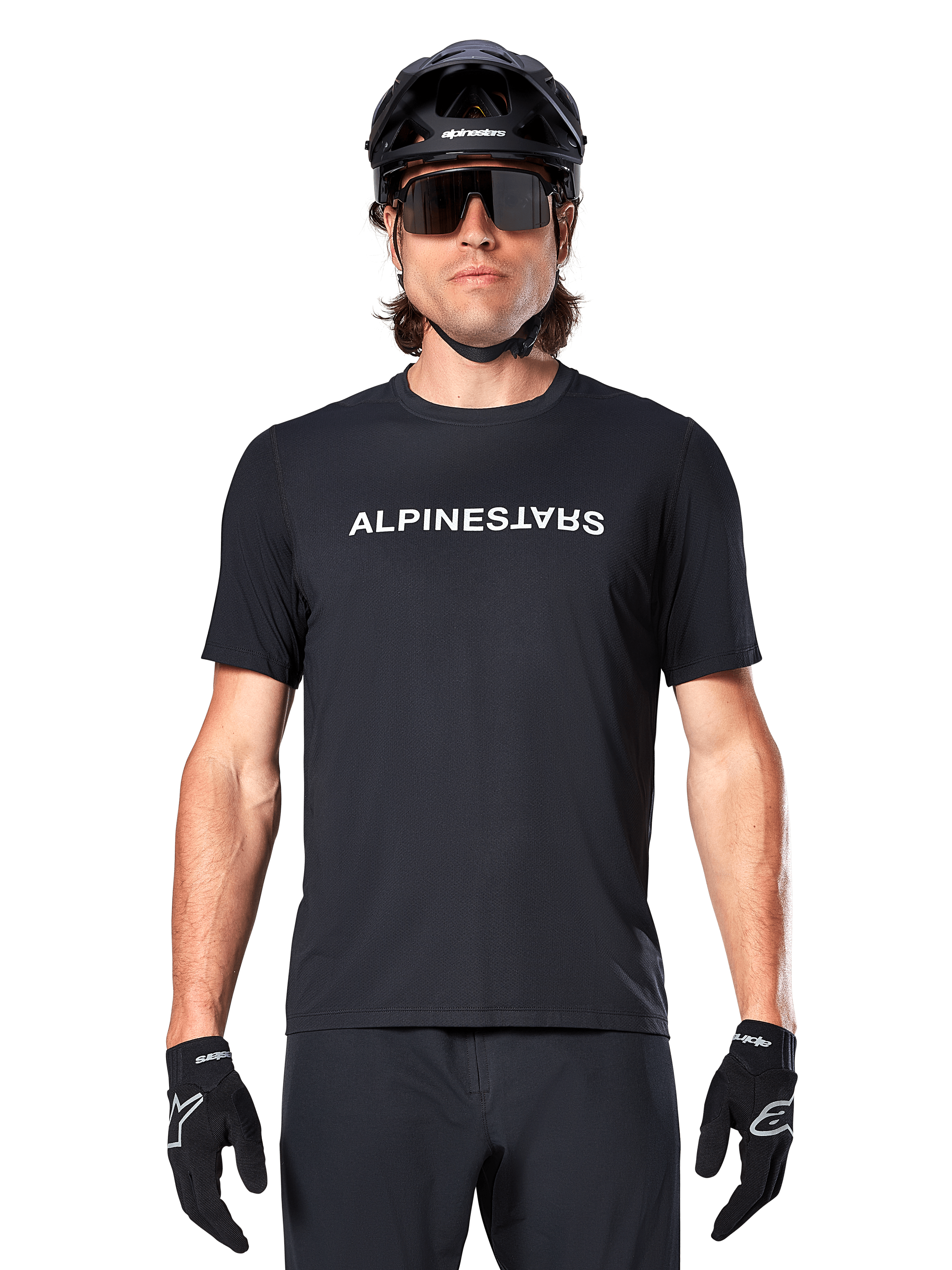 MTB-cyklist iförd Alpinestars A-Dura Switch kortärmad tröja i svart, med vit ordmärkeslogotyp på bröstet, stylad med en svart hjälm, stora solglasögon och svarta handskar, professionella cykelkläder för stigcykling