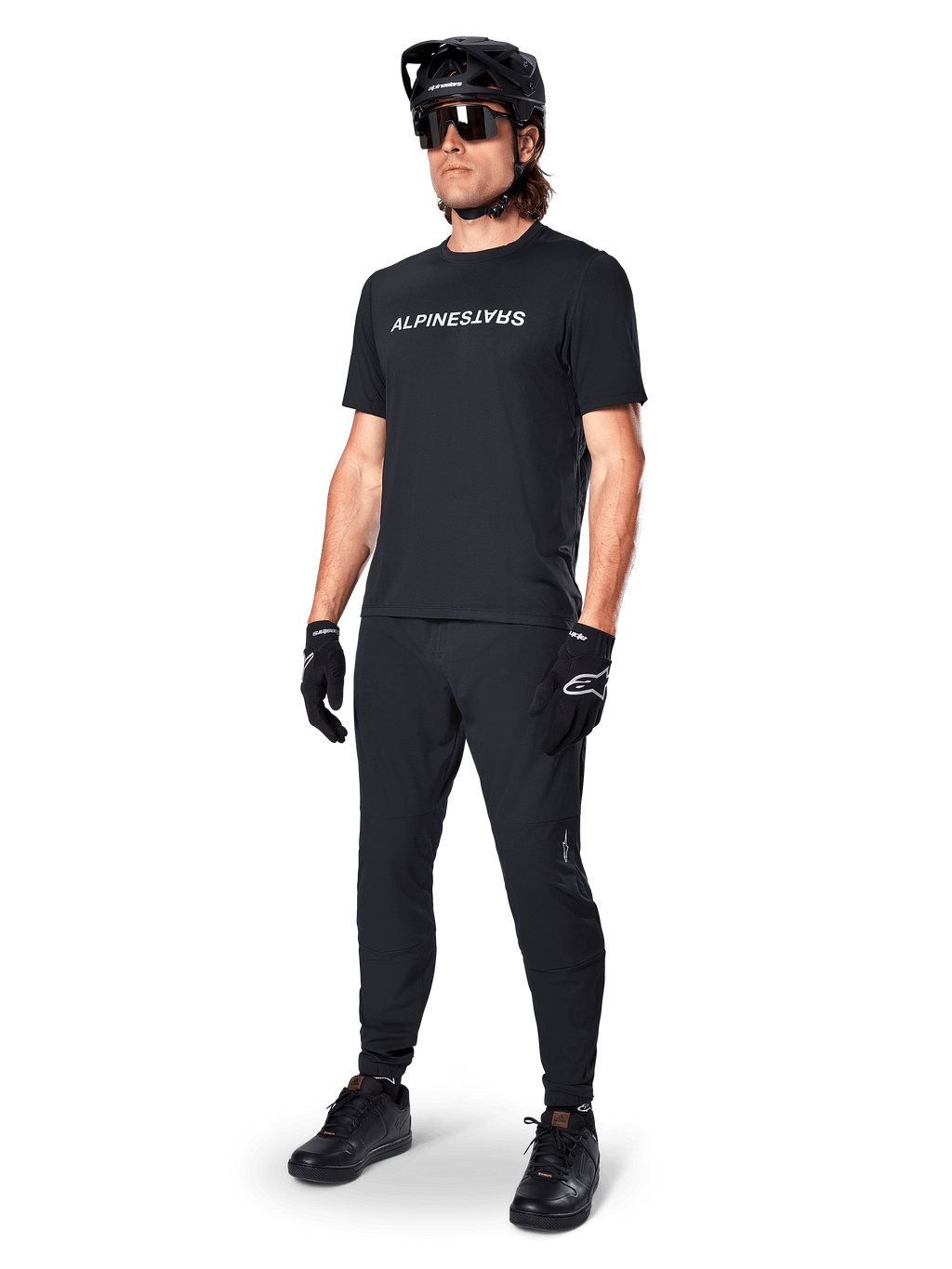 Alpinestars A-Dura Switch kortärmad tröja, svart, bärs av modell med matchande svarta MTB-byxor, hjälm och handskar, med ett vitt Alpinestars-ordmärke på bröstet, högpresterande mountainbikekläder