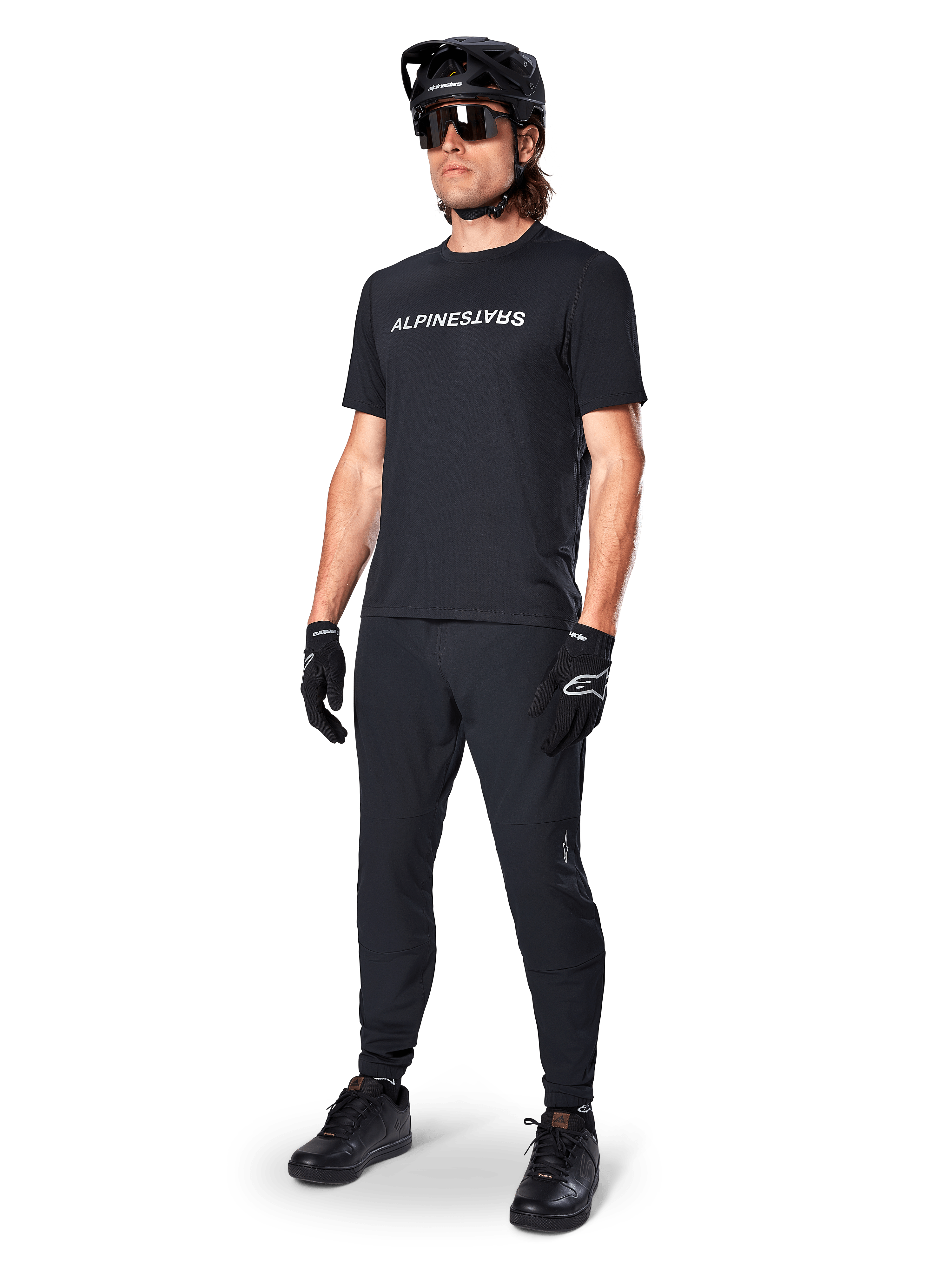 Alpinestars A-Dura Switch kortärmad tröja, svart, bärs av modell med matchande svarta MTB-byxor, hjälm och handskar, med ett vitt Alpinestars-ordmärke på bröstet, högpresterande mountainbikekläder