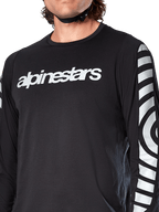 Alpinestars A-Dura Dri Oscar långärmad tröja, Black Reflective, närbild som visar vit Alpinestars-logotyp på bröstet och reflekterande cirkulär grafik på ärmarna, tekniska cykelkläder för mountainbike