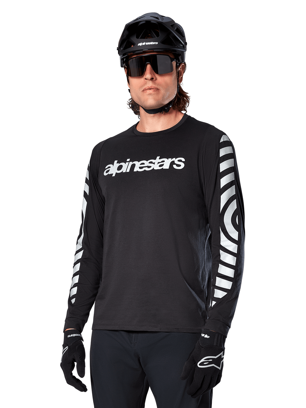 Alpinestars A-Dura Dri Oscar långärmad tröja, MTB-tröja, svart med reflekterande detaljer, vit textlogotyp på bröstet och framträdande reflekterande cirkulär grafik på ärmarna, bärs med svart hjälm och solglasögon, tekniskt fukttransporterande material för terrängcykling