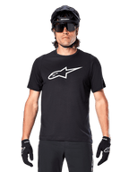 Alpinestars A-Dura Dri Oscar-tröja, kortärmad, svart reflekterande, bärs med svart MTB-hjälm, solglasögon och handskar, framträdande vit logotyp på bröstet, funktionskläder för mountainbike