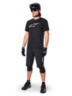 Mountainbike-cyklist som bär Alpinestars A-Dura Dri Oscar kortärmad tröja i Black Reflective, med en stor vit logotyp på bröstet, kombinerat med matchande svarta MTB-shorts, handskar och hjälm, tekniska cykelkläder för terrängprestanda
