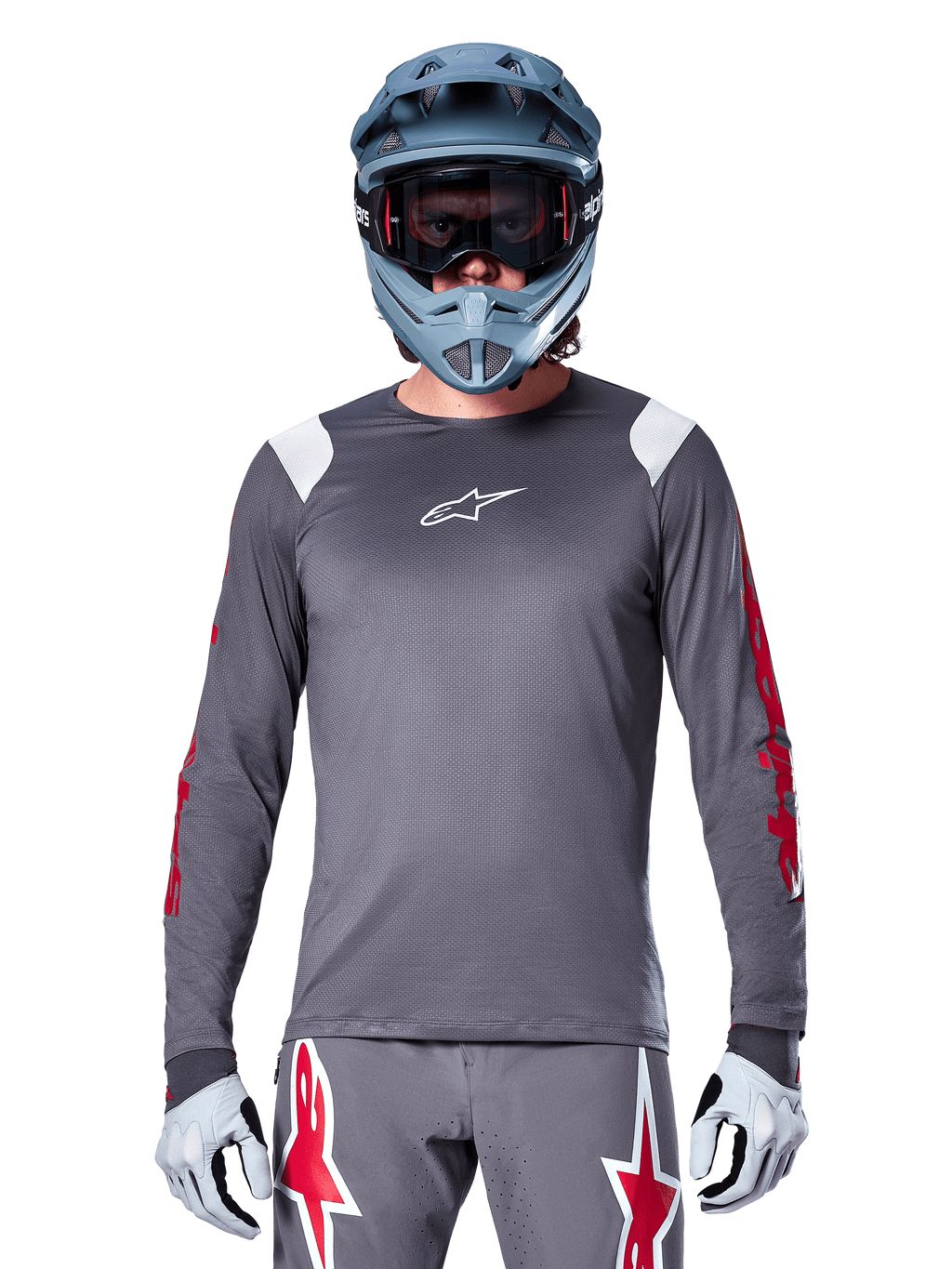 MTB-cyklist iförd Alpinestars A-Supra Astar långärmad tröja, mörkgrå med röd grafik på ärmarna och vita detaljer på axlarna, matchande grå byxor med röda stjärnlogotyper, blå fullfacehjälm och goggles, koordinerad cykelutrustning för terrängkörning