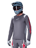 Alpinestars A-Supra Astar långärmad tröja, MTB-tröja, mörkgrå med röda och vita detaljer, prestandapassform, bärs med matchande grå byxor med röd och vit stjärngrafik, komplett outfit för terrängcykling med fullface-hjälm och handskar