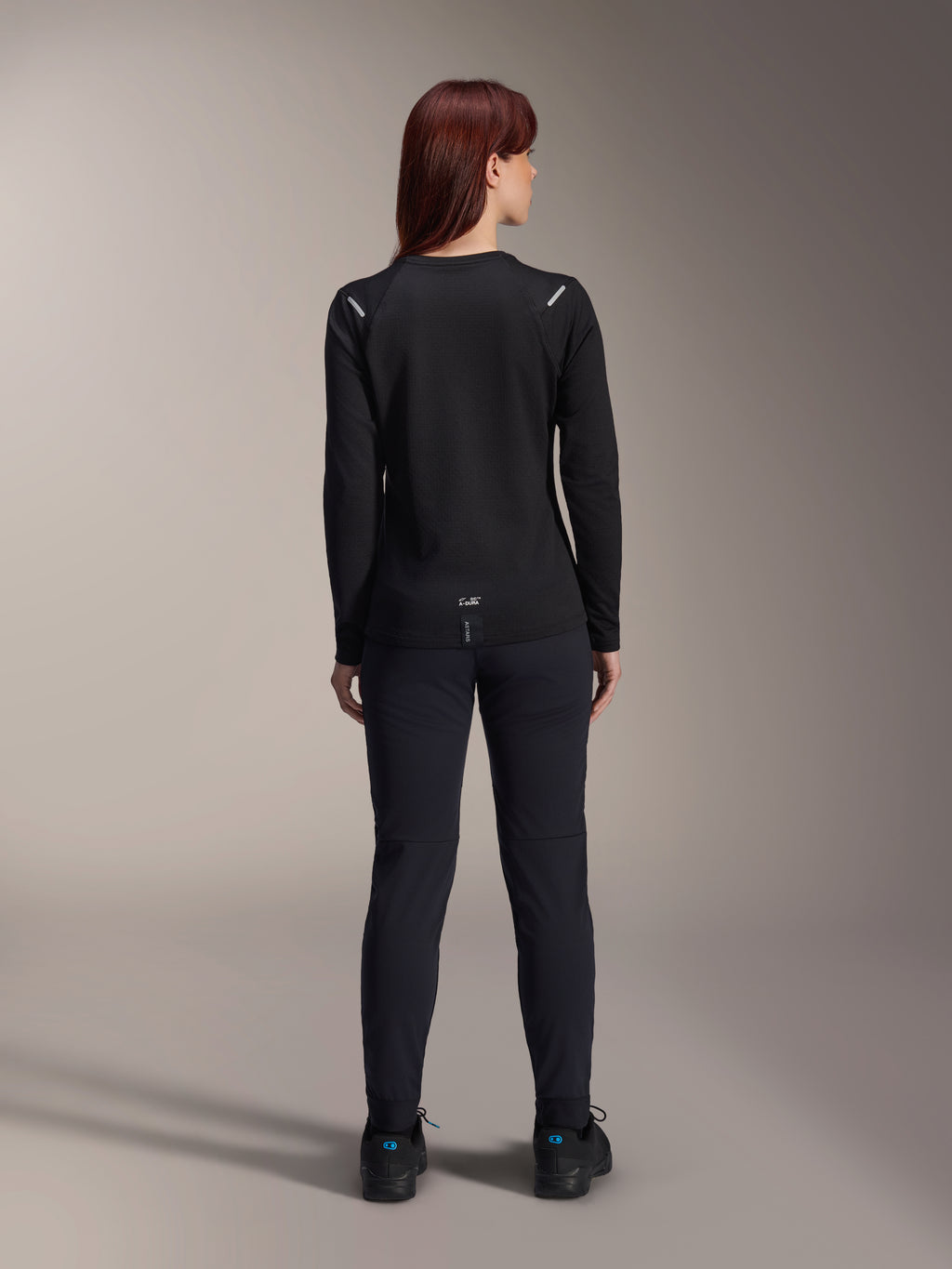 Alpinestars Stella A-Dura Thermal-tröja för dam, vy bakifrån, svart, långärmad cykeltröja med isolerande fleece, bärs med matchande svarta byxor och skor, liten A-Dura-logotyp på nedre ryggen, reflekterande detaljer på axlarna, anpassad för MTB-cykling för damer