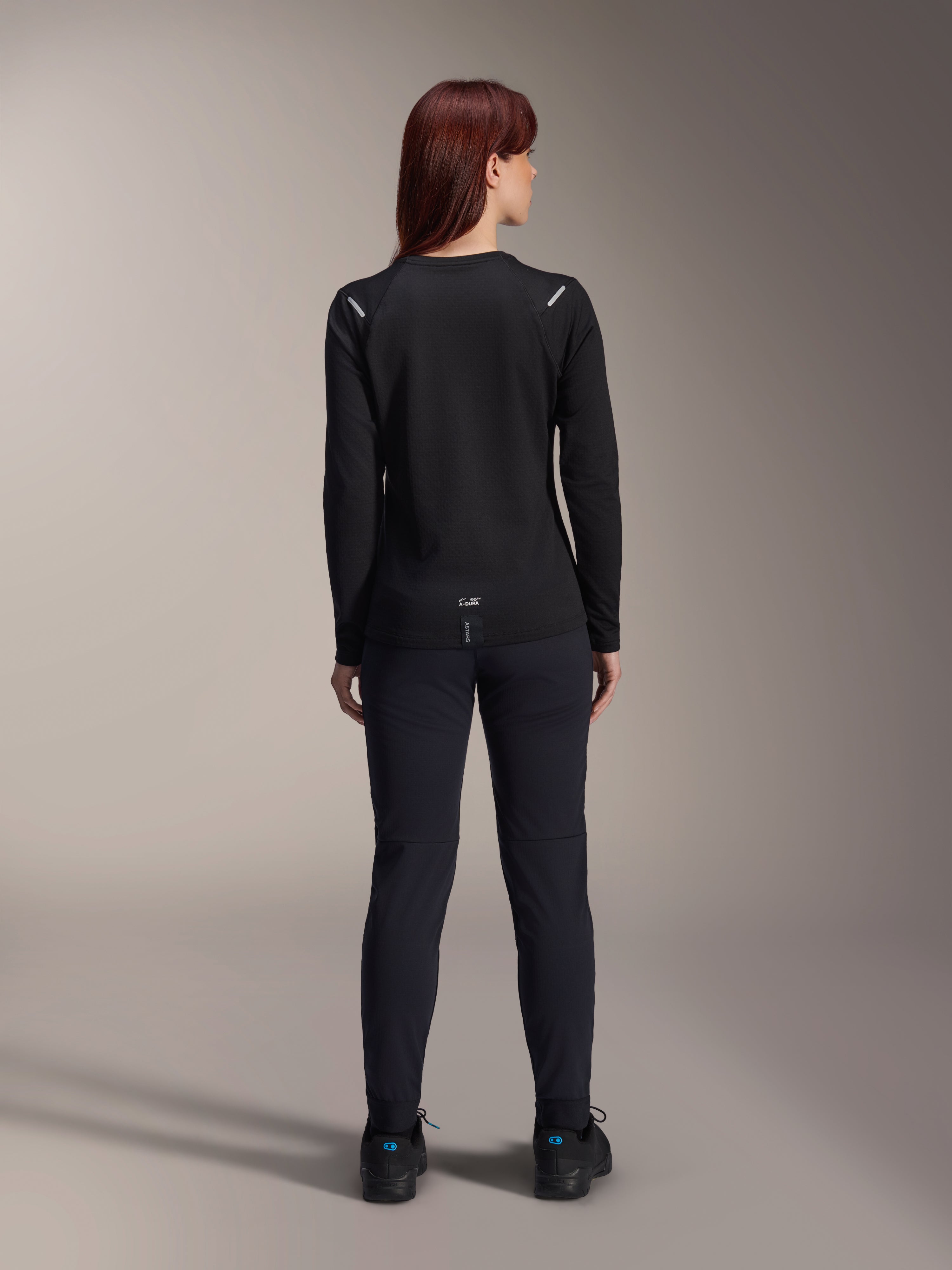 Alpinestars Stella A-Dura Thermal-tröja för dam, vy bakifrån, svart, långärmad cykeltröja med isolerande fleece, bärs med matchande svarta byxor och skor, liten A-Dura-logotyp på nedre ryggen, reflekterande detaljer på axlarna, anpassad för MTB-cykling för damer