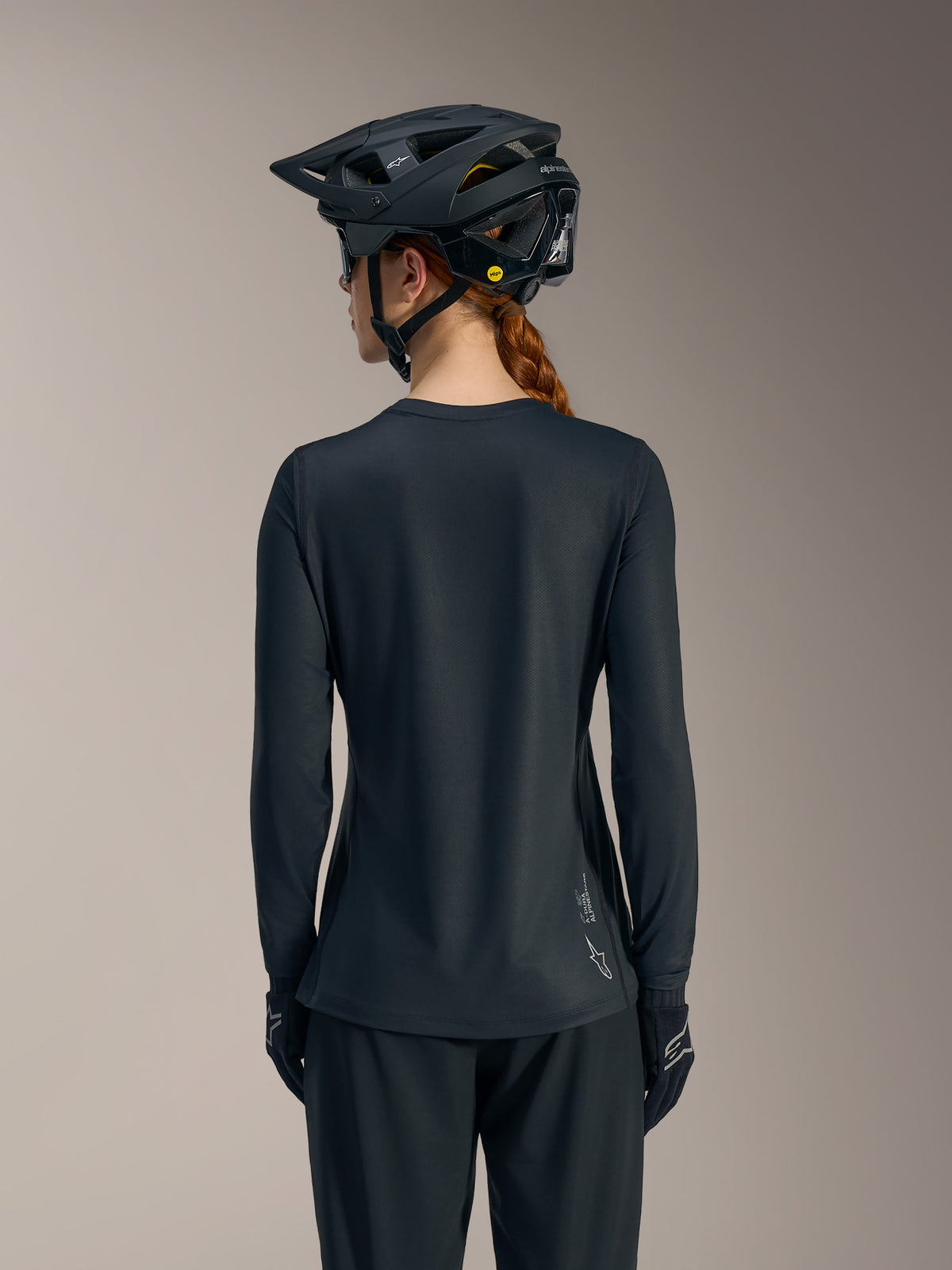 Svart långärmad Stella A-Dura Ride MTB-tröja sedd bakifrån, med diskret Alpinestars-logotyp på nedre fållen.