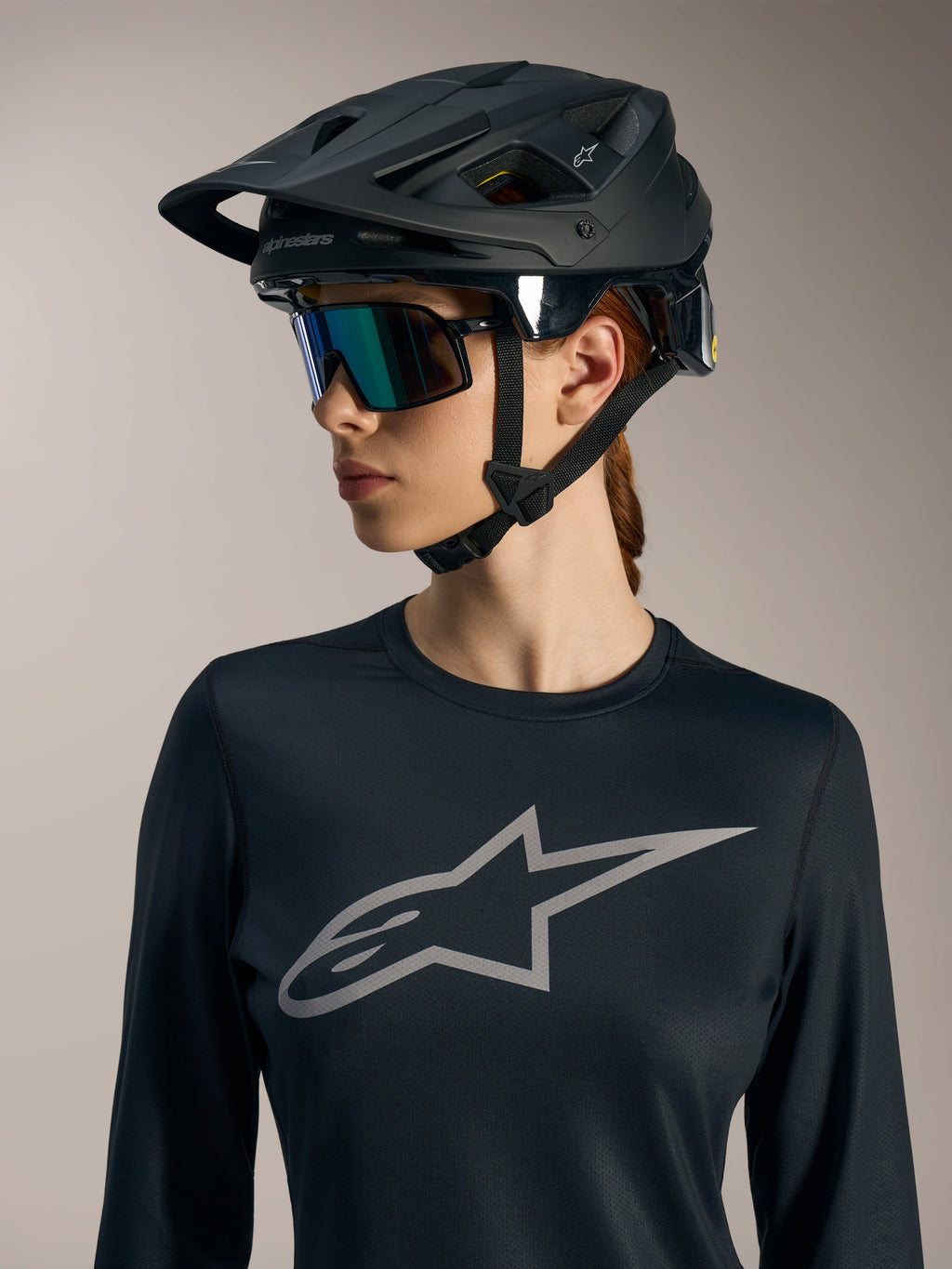 Svart Stella A-Dura Ride långärmad damtröja med grå Astars-logotyp på bröstet och en matt svart MTB-hjälm.