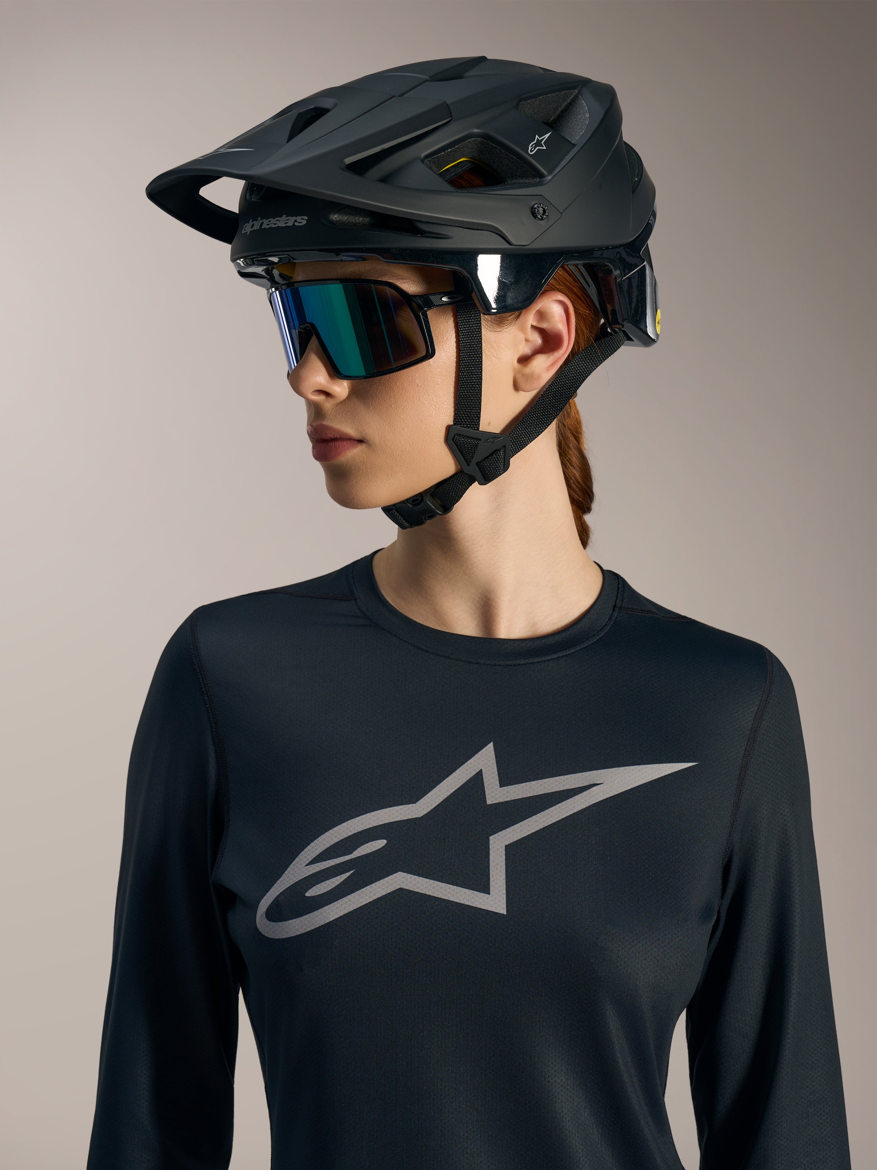 Svart Stella A-Dura Ride långärmad damtröja med grå Astars-logotyp på bröstet och en matt svart MTB-hjälm.