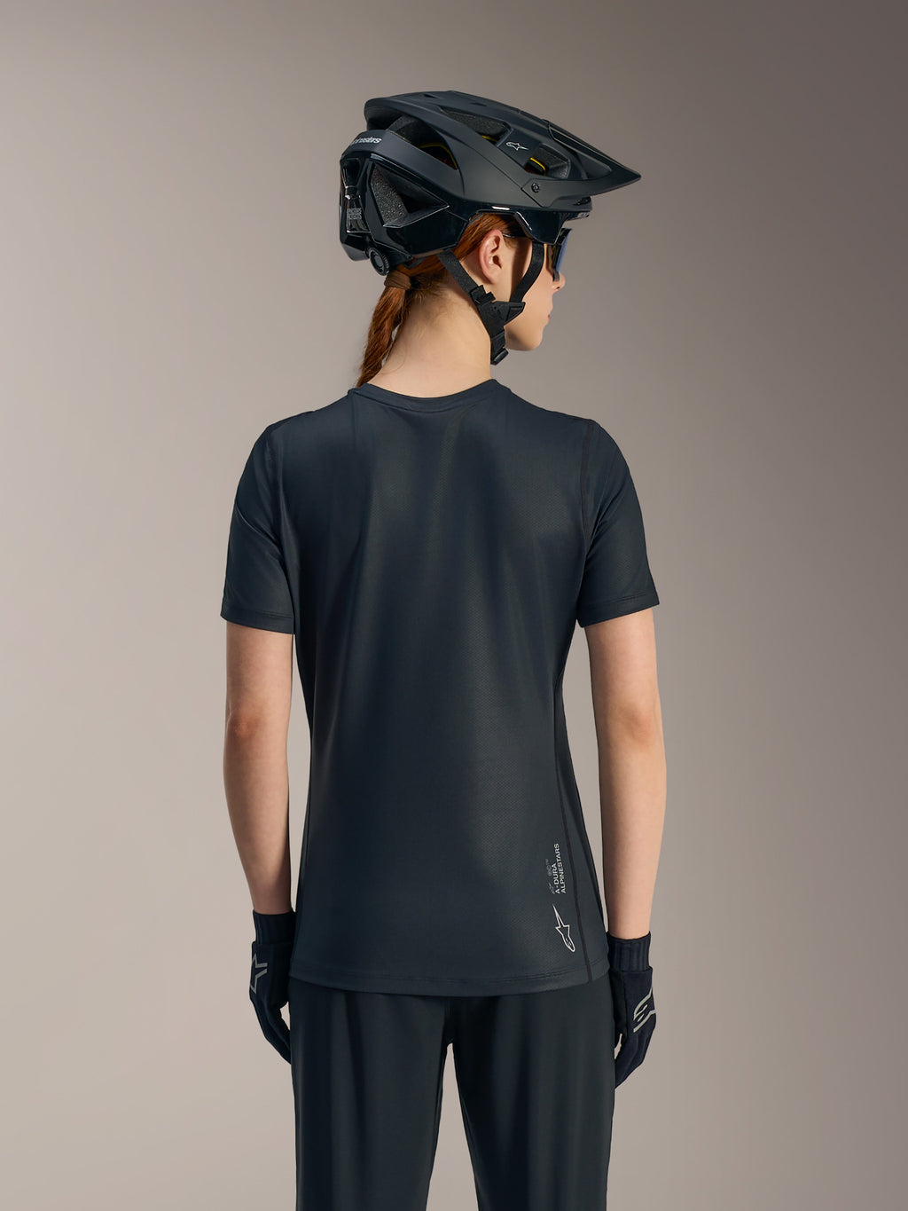 Svart Stella A-Dura Ride kortärmad cykeltröja för dam sedd bakifrån, med förlängd rygg och Alpinestars-logotyp.