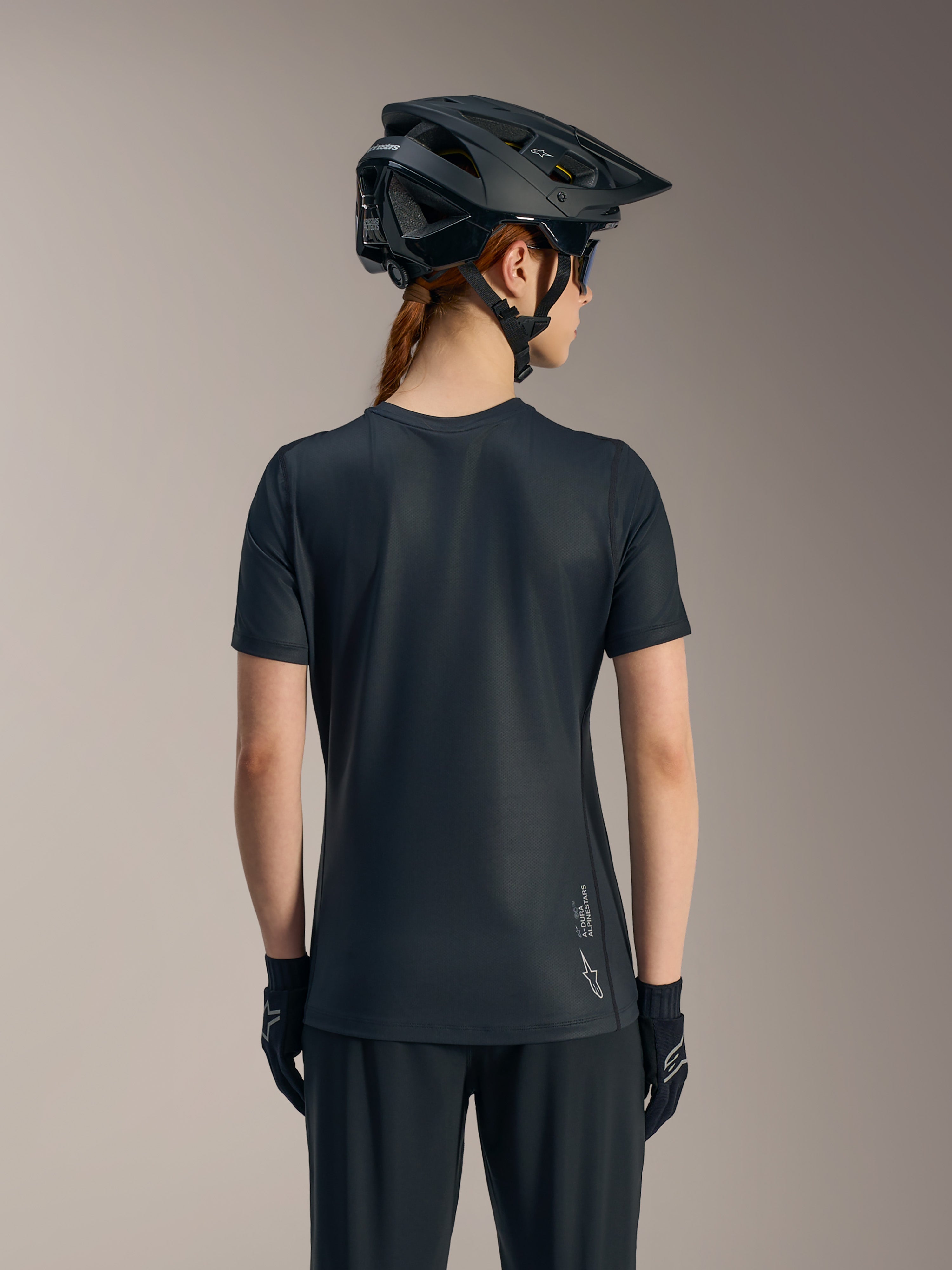 Svart Stella A-Dura Ride kortärmad cykeltröja för dam sedd bakifrån, med förlängd rygg och Alpinestars-logotyp.