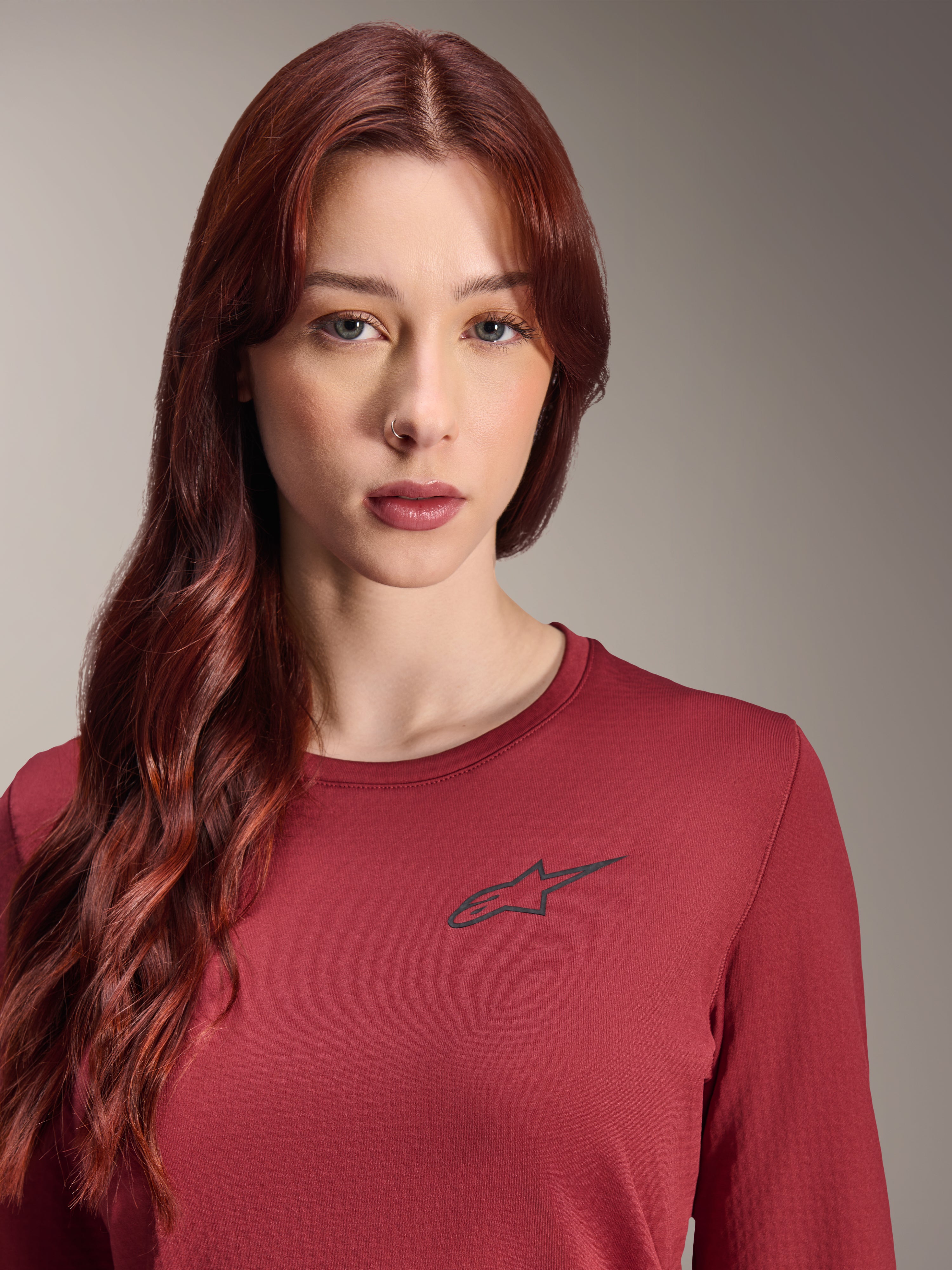 Alpinestars Stella A-Dura Thermal-tröja, långärmad MTB-tröja för dam, vinröd, närbild med en svart stjärnlogotyp på bröstet, isolerad teknisk utrustning för mountainbikecykling i kallt väder