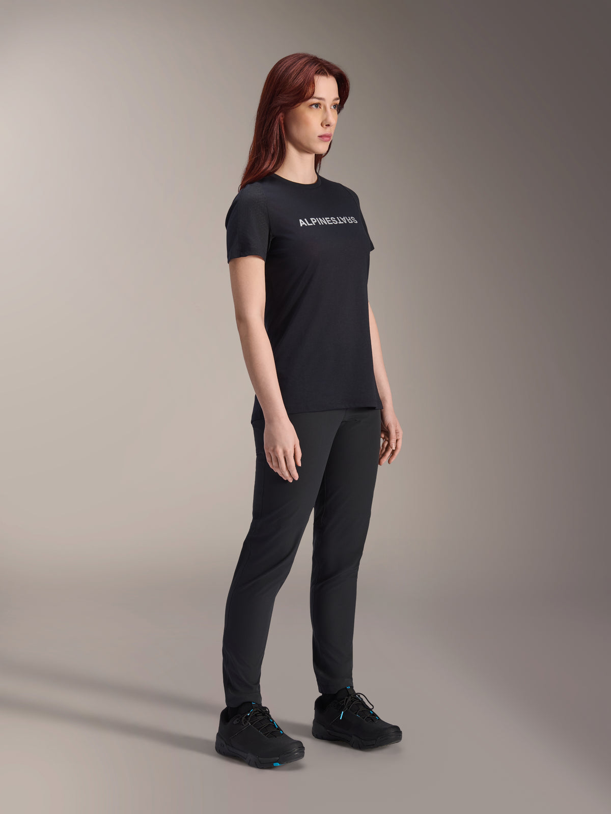 Alpinestars Stella A-Dura Dri Switch Jersey, kortärmad cykeltröja, svart med vit Alpinestars-logotyp, bärs av en kvinnlig modell med matchande svarta byxor och skor, mångsidig utrustning för mountainbike.