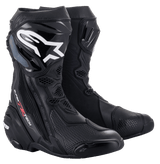 A black pair of Supertech R Boots from Alpinestars EU, showcasing white and silver detailing. These high-cut racing boots feature reinforced ankle, heel, and toe areas, with the brand's logo prominently displayed on the outer side of each boot for a sleek design.