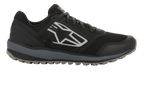 Alpinestars Meta Trail-skor, prestationslöparskor, svarta och mörkgrå, sidoprofil med en stor vit geometrisk Astars-logotyp, ovandel i mesh med grå mellansula och mönstrad gummisula, avslappnade paddockskor för motorsport
