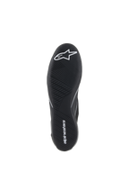 Alpinestars Supertech-skor, racingskor för bilsport, svarta, vy underifrån av den ultratunna gummiyttersulan med vit stjärnlogotyp och Alpinestars textlogotyp, med ett asymmetriskt mönster för pedalkänsla och grepp