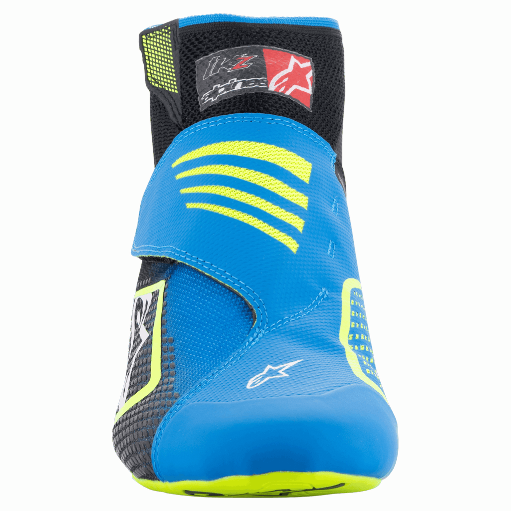 Alpinestars Tech-1 KZ V2-skor, kartingskor, svart, emaljblå och fluogul, vy framifrån som visar den sömlösa stickade ovandelen, klarblå rem med gula detaljer och svart ankelkrage.