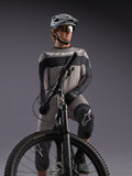 Grå Alpinestars A-Dura Race långärmad tröja på en MTB-cyklist, med svarta detaljer och professionell utrustning.
