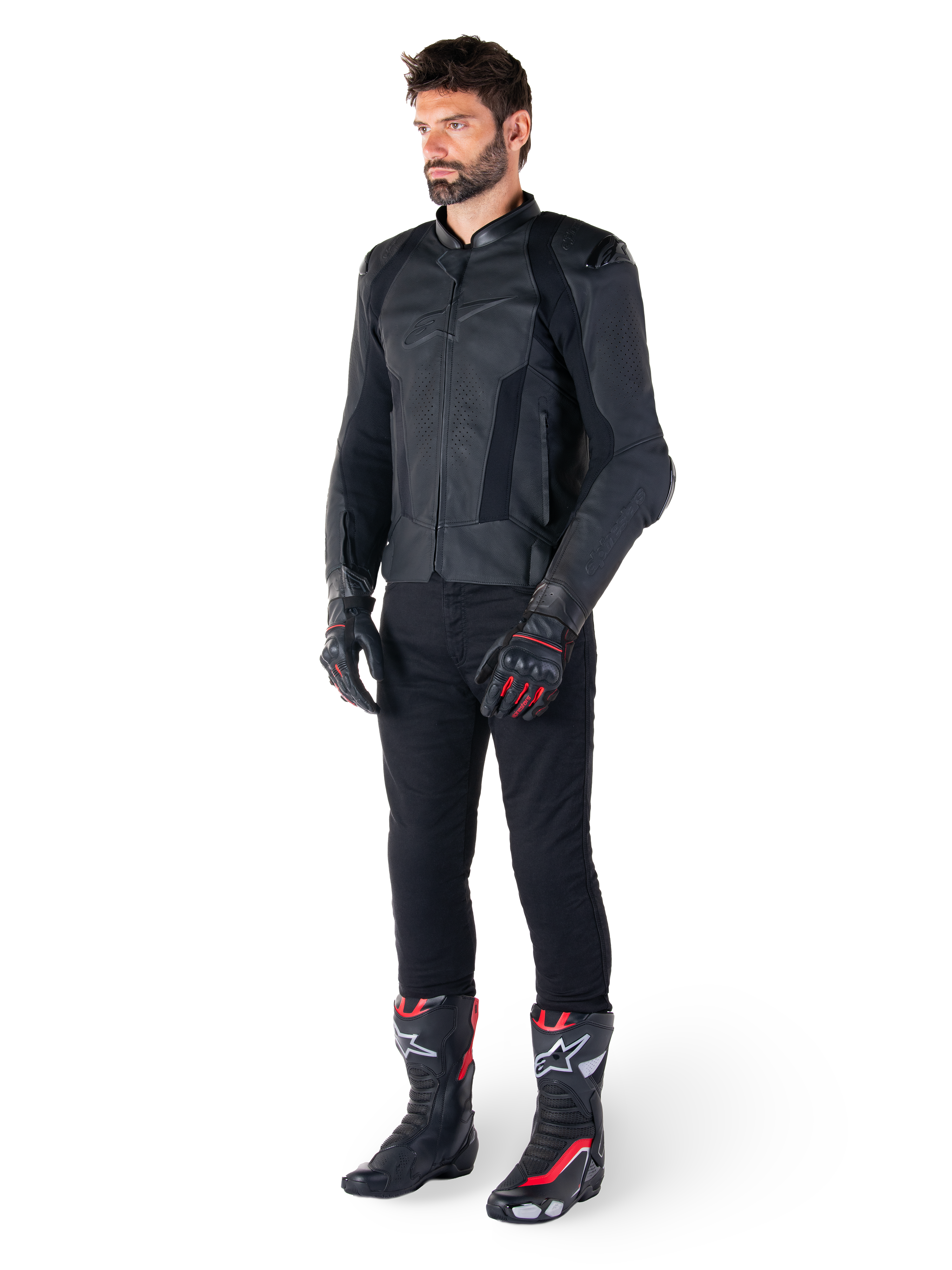 Alpinestars Missile V3 läderjacka, svart, bärs av en förare med svarta byxor och svart-röda racinghandskar och stövlar, med perforerade läderpaneler och elegant monokrom logotyp, professionell racing-estetik