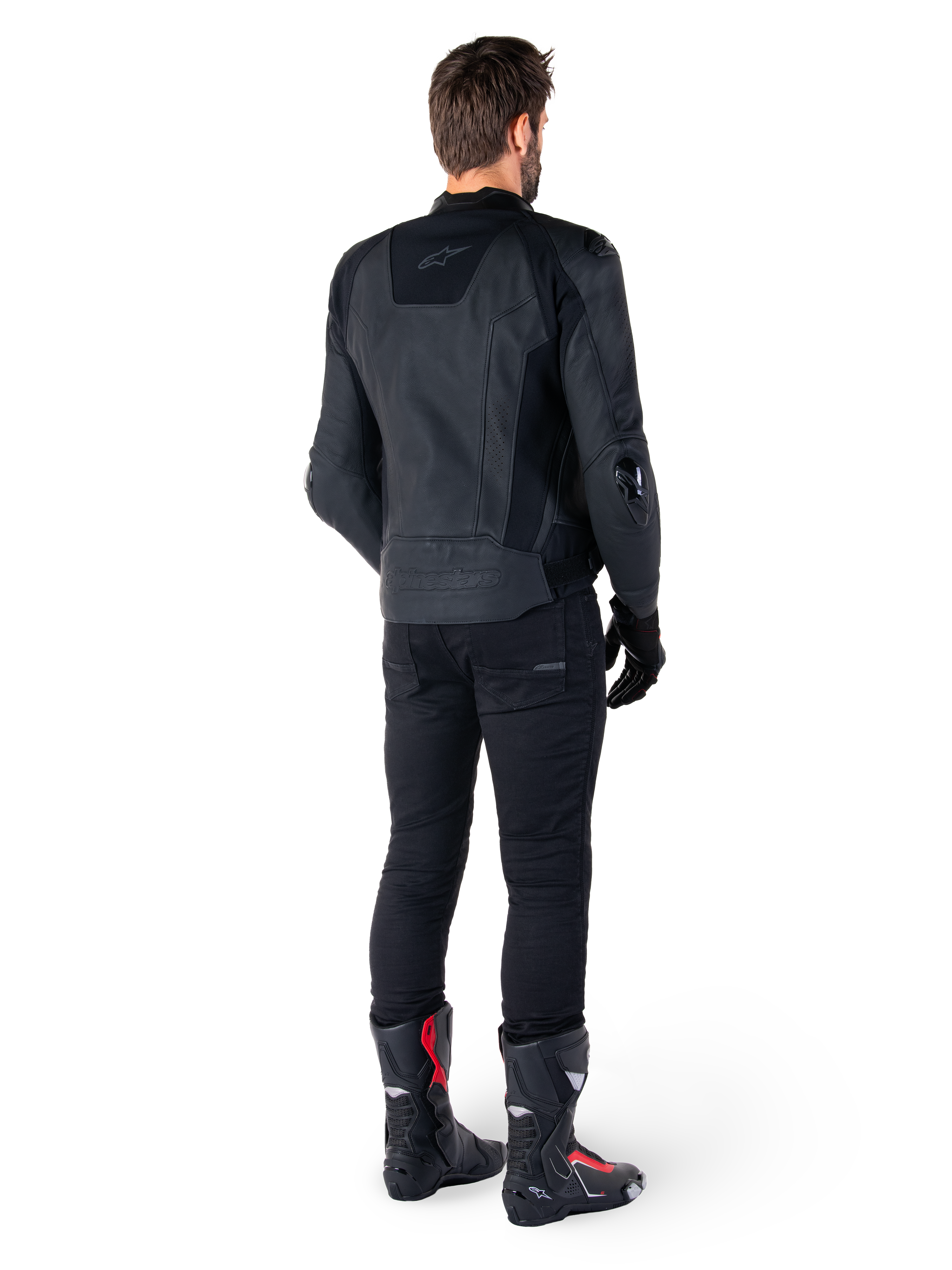 Alpinestars Missile V3 skinnjacka i svart, sedd bakifrån på en förare, bärs med svarta byxor och svart-röda racingstövlar, smidig skinnkonstruktion med logotyper ton-i-ton och en sportig race-passform