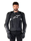 Alpinestars Missile V3 läderjacka, svart med vita logotyper, bärs av en modell med svarta körhandskar, premium motorcykelracingjacka i läder med perforerade ventilationspaneler och prestandafunktioner