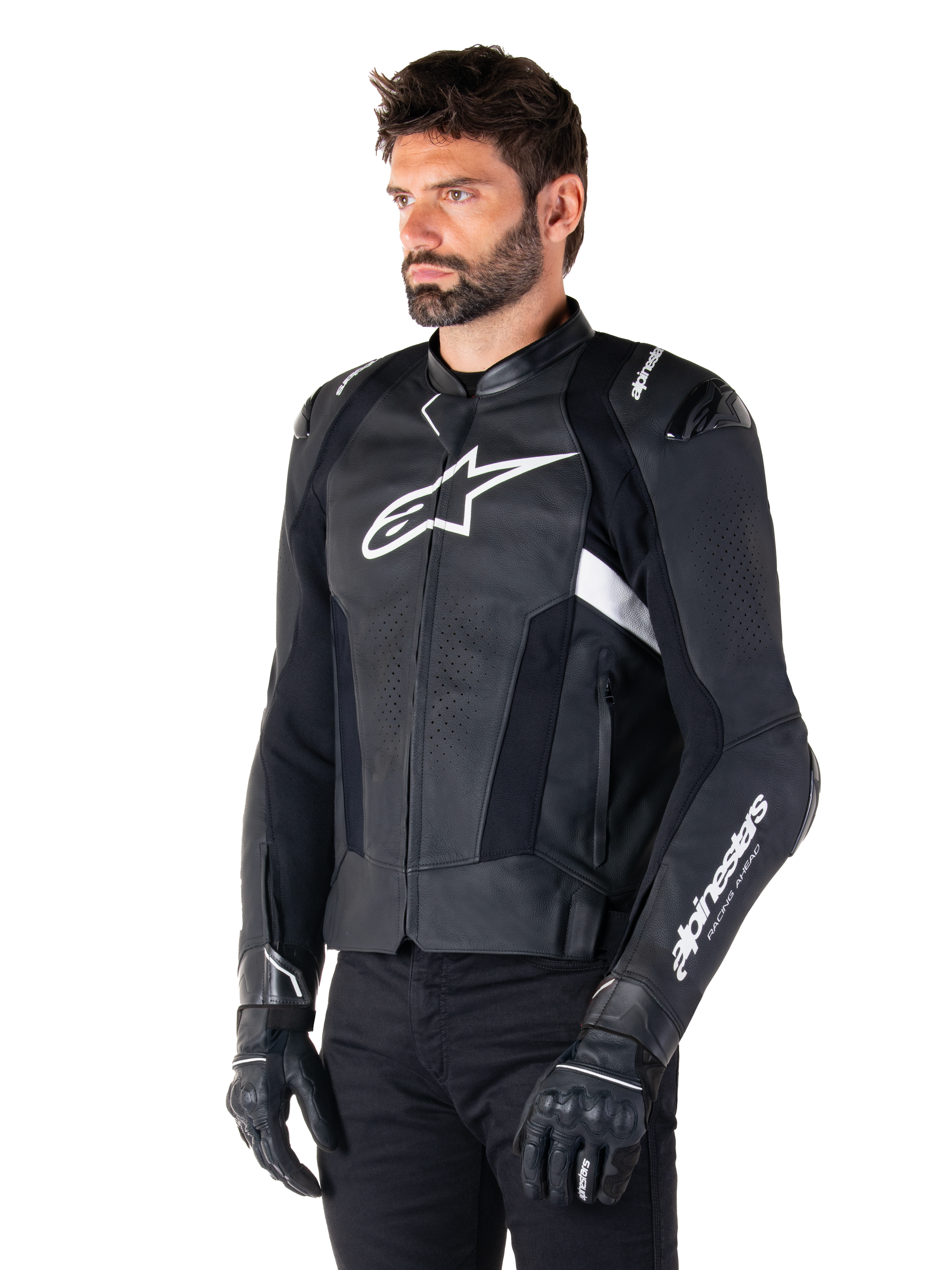 Alpinestars Missile V3 skinnjacka, svart och vit, bärs av en man med svarta körhandskar, med en framträdande vit Alpinestars-logotyp på bröstet, externa axelsliders och perforerade paneler för en racinginspirerad look.