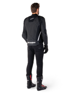 Alpinestars Missile V3 Skinnjacka, svart och vit, vy bakifrån på förare, med framträdande vit Alpinestars-logotyp på nedre delen av ryggen och en liten logotyp på övre delen, bärs med svarta byxor och racingstövlar, premium skinnkonstruktion för motorcykelracing