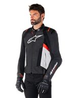 Alpinestars Missile V3 läderjacka, svart, vit och röd fluo, racing-sportjacka för motorcykel buren av en modell med svarta handskar och byxor, perforerade läderpaneler och tydlig Alpinestars-branding