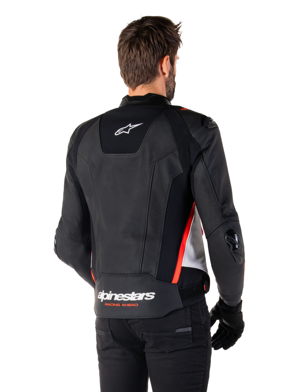 Alpinestars Missile V3 Läderjacka, ryggvy på en förare, svart, vit och röd fluo, med framträdande Alpinestars-logotyp och texten 'RACING AHEAD' på nedre delen av ryggen, premium läderkonstruktion med tekniska stretchpaneler och skyddande TPU-sliders, buren med svarta handskar och byxor.