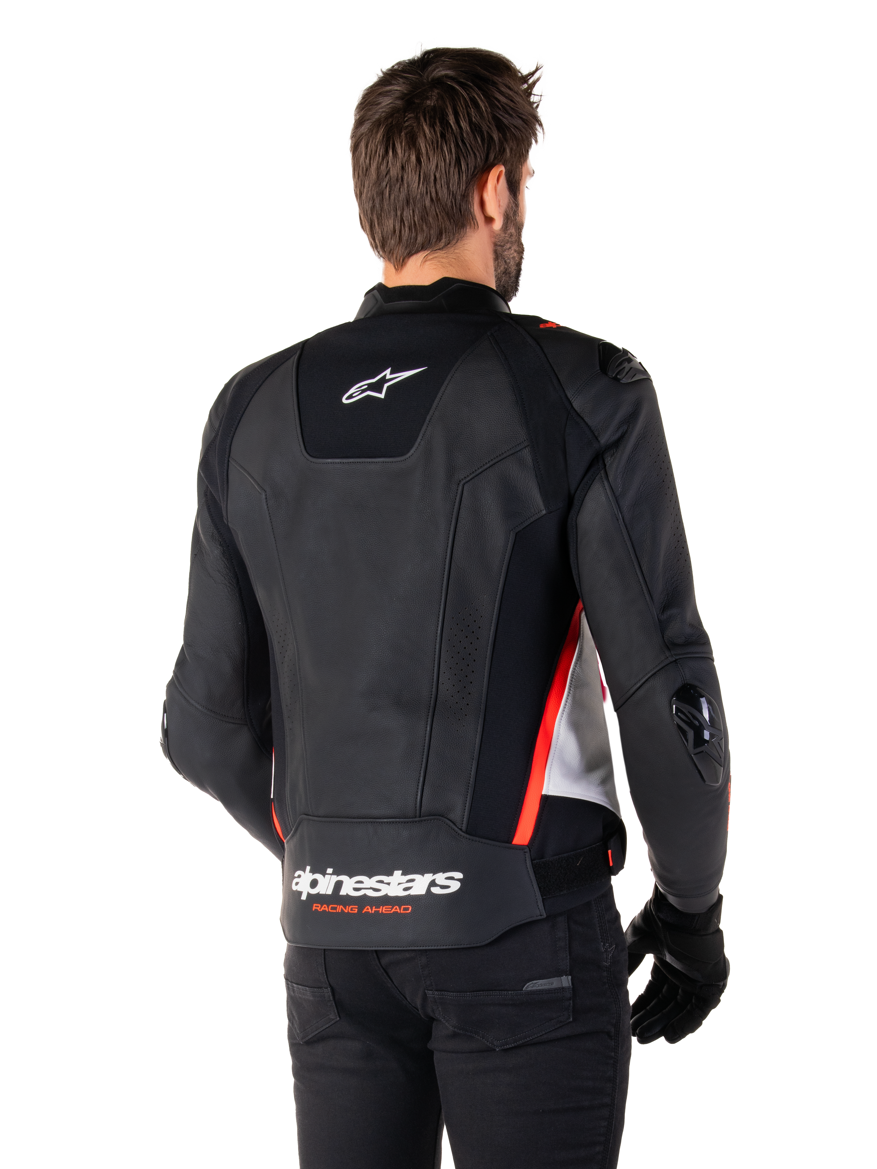 Alpinestars Missile V3 Läderjacka, ryggvy på en förare, svart, vit och röd fluo, med framträdande Alpinestars-logotyp och texten 'RACING AHEAD' på nedre delen av ryggen, premium läderkonstruktion med tekniska stretchpaneler och skyddande TPU-sliders, buren med svarta handskar och byxor.