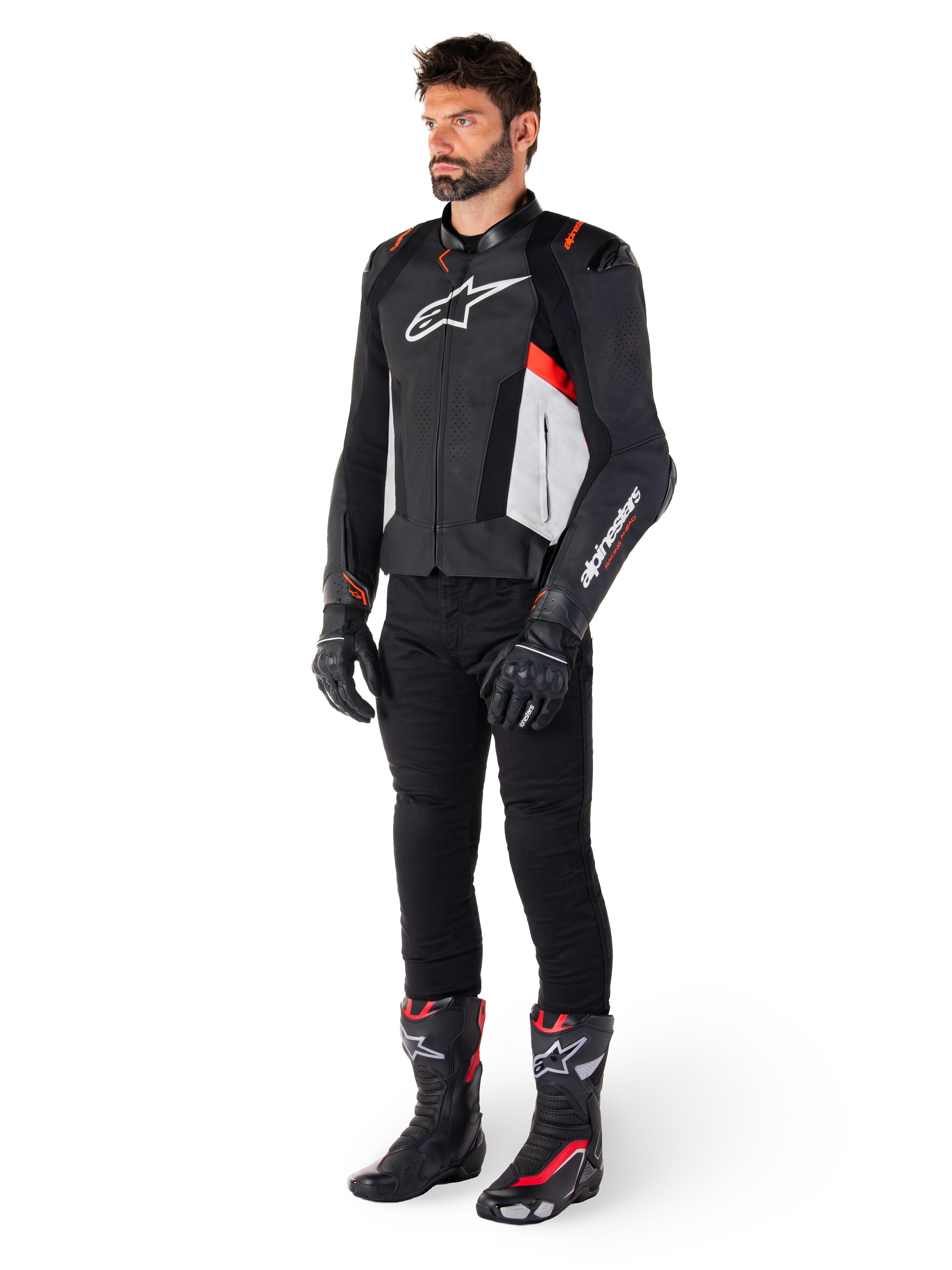 Manlig modell iklädd Alpinestars Missile V3 läderjacka i svart, vitt och röd fluo, kombinerad med svarta motorcykelbyxor, handskar och stövlar, tillverkad i premium nötläder med framträdande Alpinestars-logotyper, professionell racing-sportestetik