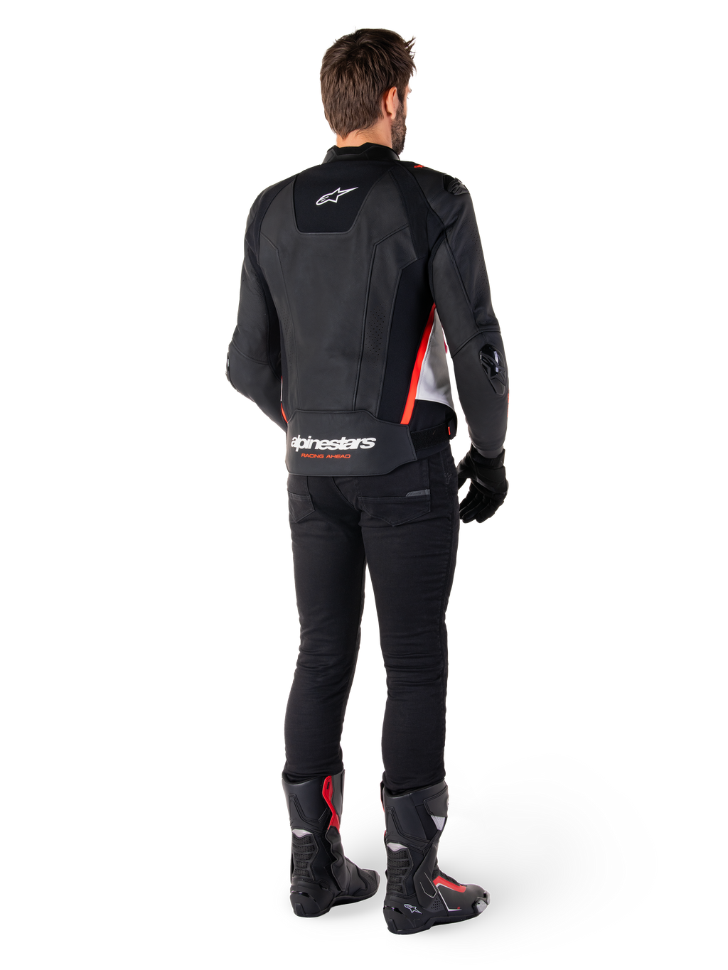 Alpinestars Missile V3 läderjacka i svart, vitt och röd fluo, vy bakifrån på en manlig förare, med Alpinestars-logotyper på övre och nedre ryggen, kombinerad med svarta byxor och motorcykelstövlar, racinginspirerad sportjacka i läder.