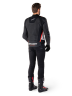 Alpinestars Missile V3 läderjacka i svart, vitt och röd fluo, vy bakifrån på en manlig förare, med Alpinestars-logotyper på övre och nedre ryggen, kombinerad med svarta byxor och motorcykelstövlar, racinginspirerad sportjacka i läder.
