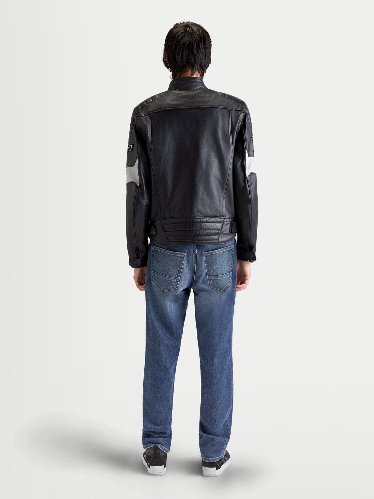Alpinestars Revern Leather Jacket, men's urban motorcycle leather jacket in black and metal gray, rear profile view on a model wearing jeans, showcasing distressed bovine leather and heritage styling.