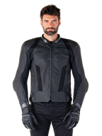 Alpinestars Missile V3 Airflow läderjacka, svart racingjacka för motorcykel, bärs av en modell med svarta handskar och byxor, med perforerade läderpaneler, meshventilation och externa axelskydd, premiumläderkonstruktion för sportkörning.