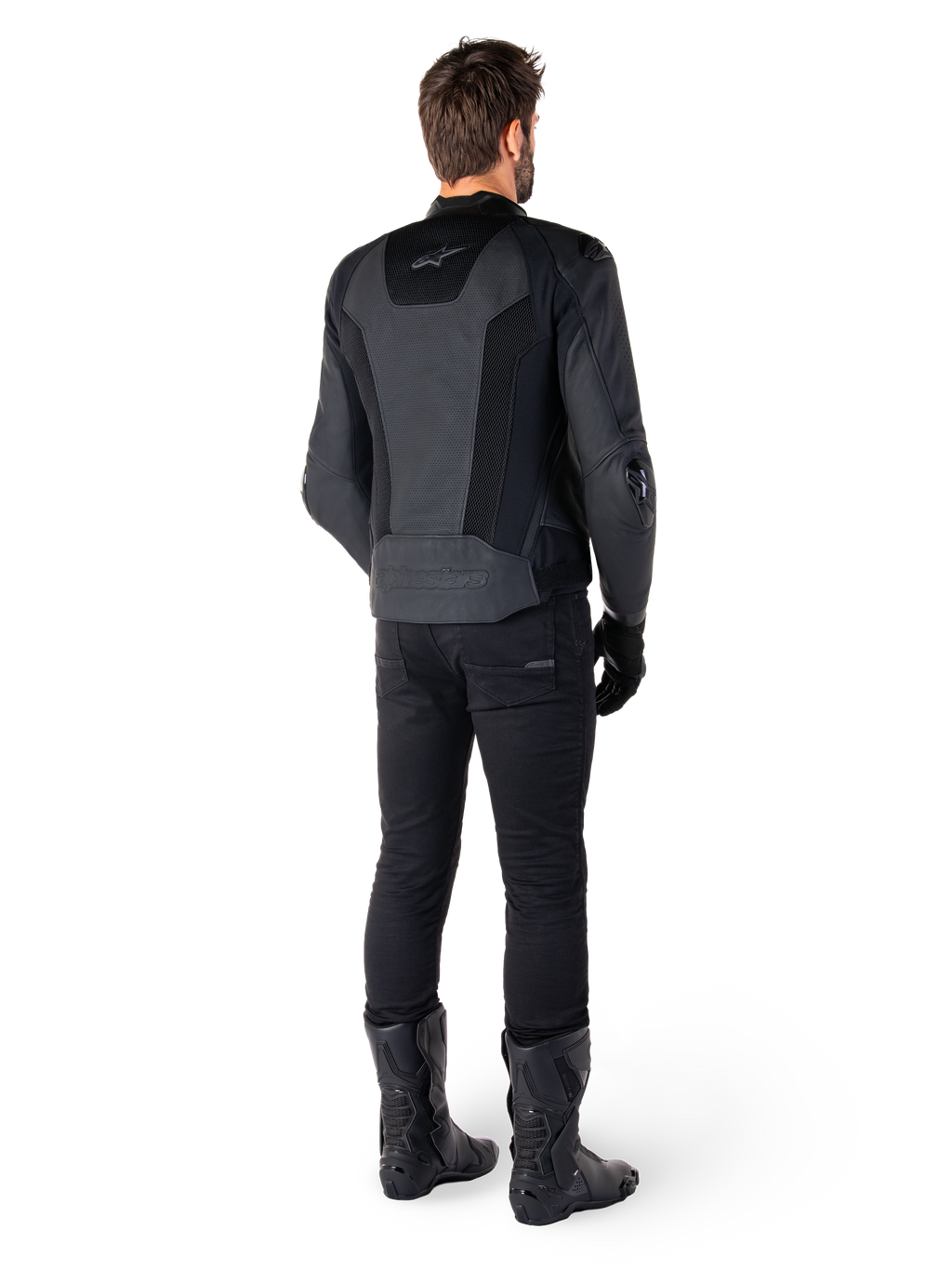 Bakifrån vy av en man klädd i Alpinestars Missile V3 Airflow skinnjacka i svart, med omfattande perforerade paneler för ventilation, matchad med svarta körbyxor och stövlar, vilket ger en strömlinjeformad racingestetik.