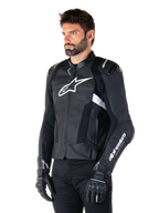 Man som bär Alpinestars Missile V3 Airflow Leather Jacket, svart och vit motorcykeljacka, premiumperforerat läder för luftflöde, vit Alpinestars-logotyp på bröstet och ärmen, racinginspirerad sportpassform, bärs med svarta handskar och byxor.