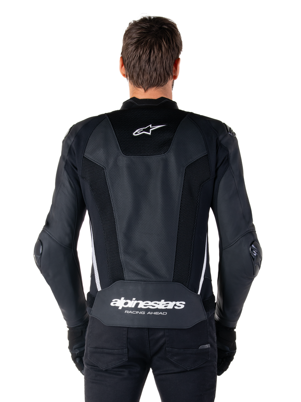 Alpinestars Missile V3 Airflow läderjacka, svart och vit, sedd bakifrån på en förare, med omfattande perforerade läderpaneler, vita sidodetaljer, Alpinestars stjärnlogotyp på den övre delen av ryggen och 'alpinestars RACING AHEAD'-logotyp på den nedre delen av ryggen.