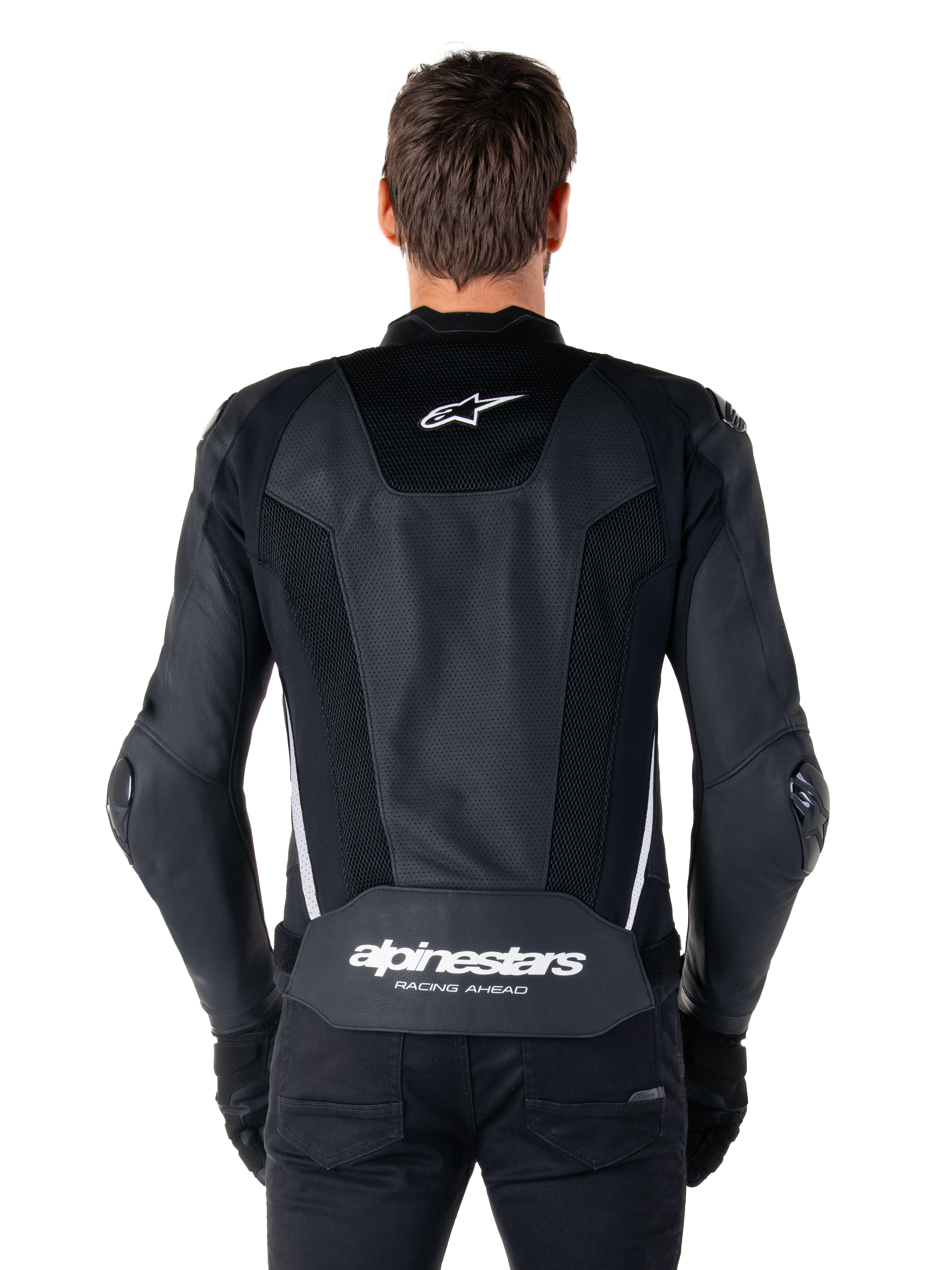Alpinestars Missile V3 Airflow läderjacka, svart och vit, sedd bakifrån på en förare, med omfattande perforerade läderpaneler, vita sidodetaljer, Alpinestars stjärnlogotyp på den övre delen av ryggen och 'alpinestars RACING AHEAD'-logotyp på den nedre delen av ryggen.