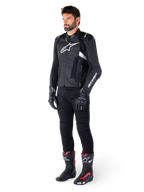 Alpinestars Missile V3 Airflow läderjacka, svart och vit, bärs av en manlig modell med svarta körbyxor, svarta handskar och racingstövlar med röda och vita detaljer, med perforerat läder och vit logotyp, prestandainriktad racingutrustning för motorcykel