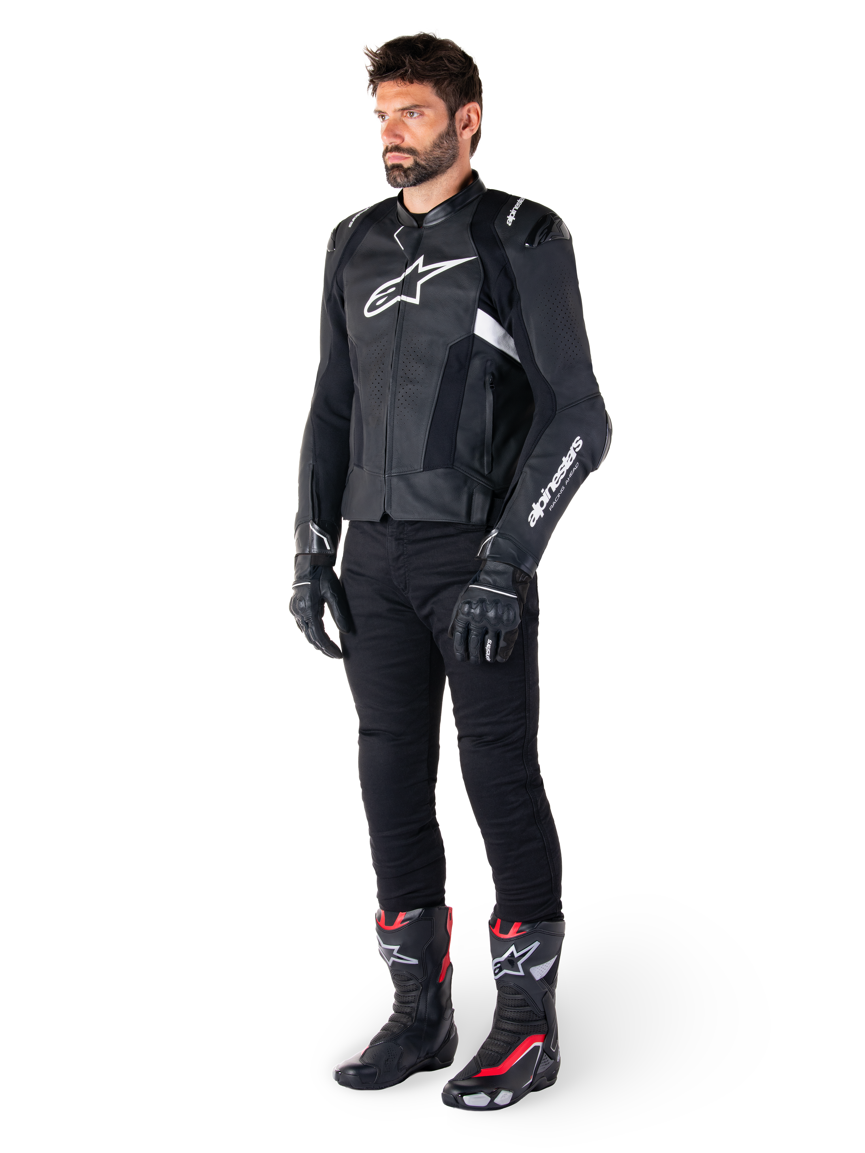 Alpinestars Missile V3 Airflow läderjacka, svart och vit, bärs av en manlig modell med svarta körbyxor, svarta handskar och racingstövlar med röda och vita detaljer, med perforerat läder och vit logotyp, prestandainriktad racingutrustning för motorcykel